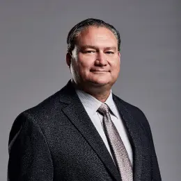 Professional headshot of Jeff Bauer wearing business attire, against a plain grey background.