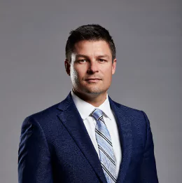 Professional headshot of Nick Smart wearing business attire, against a plain grey background.