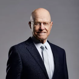 Professional headshot of Thomas Strong wearing business attire, against a plain grey background.