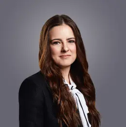 Professional headshot of Bailey Geller wearing business attire, against a plain grey background.