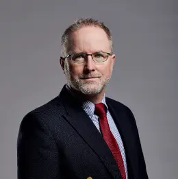 Professional headshot of Neil Chanter wearing business attire, against a plain grey background.